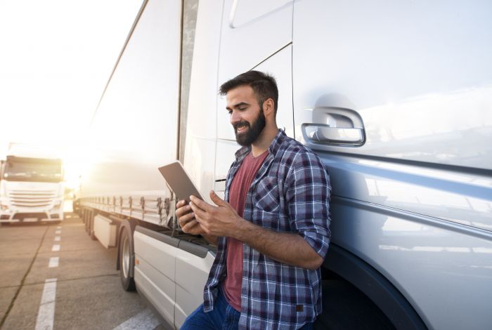 Vrachtwagenchauffeur met een tablet naast zijn vrachtwagen.